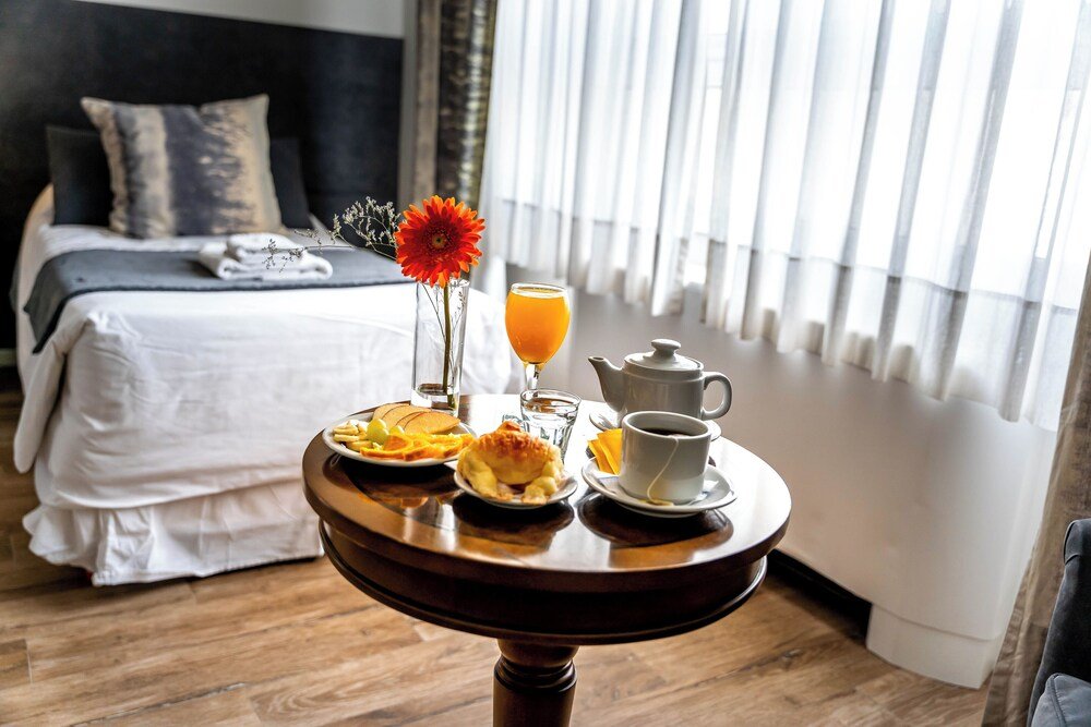 Mesa de desayuno con fruta, jugo de naranja, té y café
