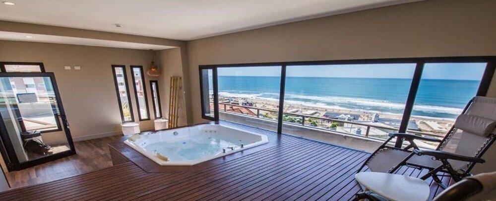 Balcón de la habitación con jacuzzi, una silla y vista al mar