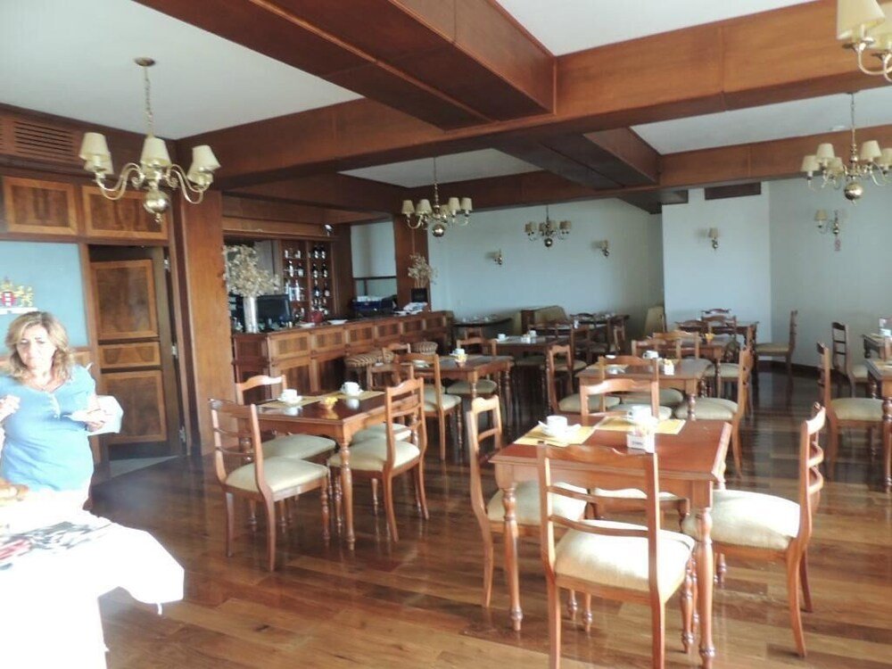 Salón comedor con mesas de madera, barra y araña