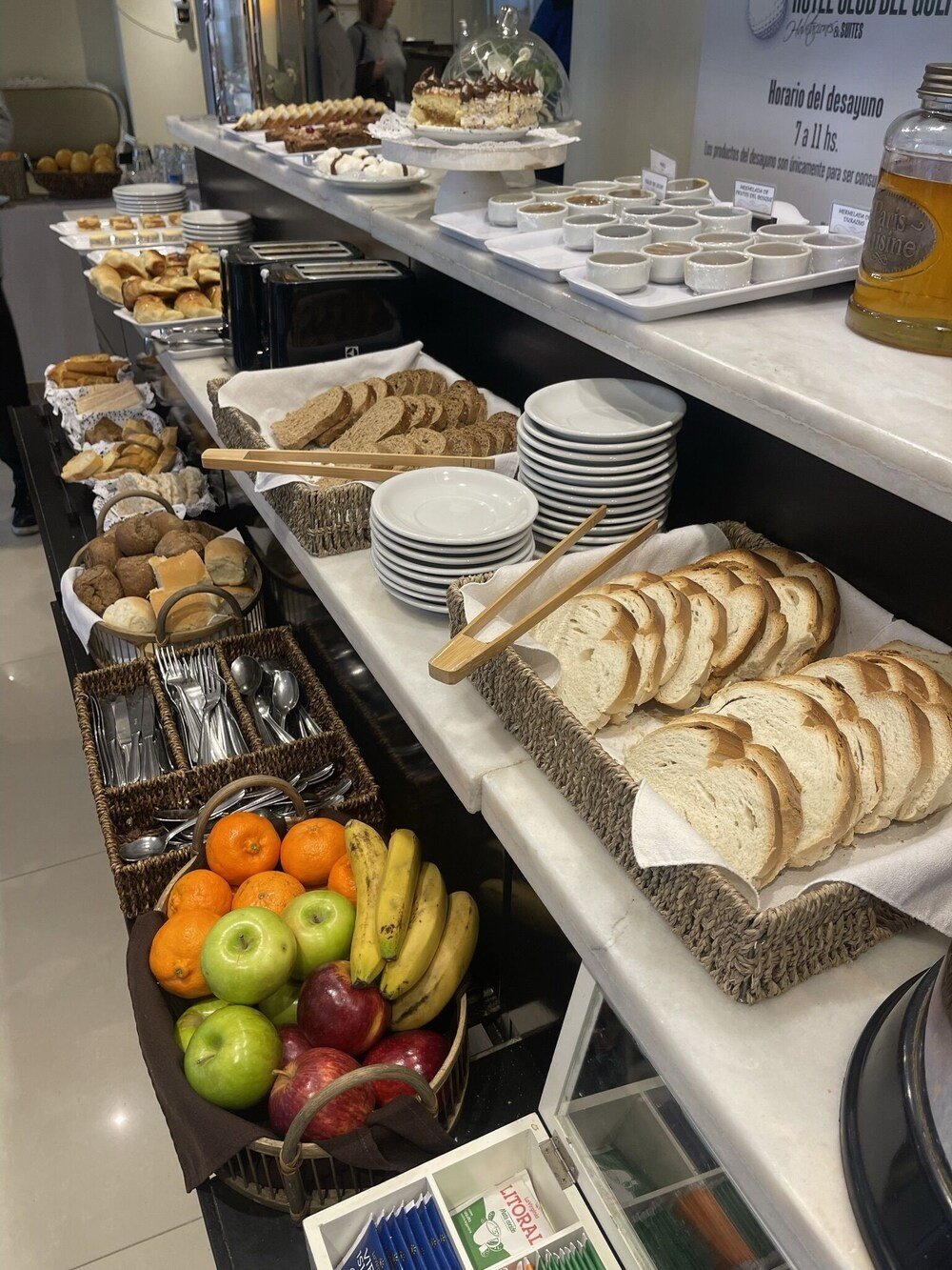 Buffet de desayuno con pan, facturas, frutas y condimentos
