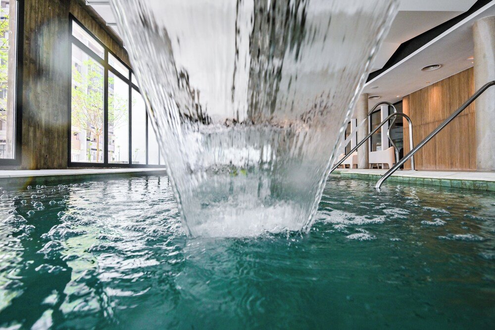 Pileta cubierta de agua clara con cascada y escalera