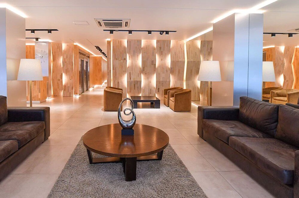 Hall con mesa ratona, sillones y pared de madera con reloj