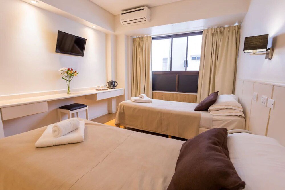 Habitación con dos camas, televisor, escritorio y cafetera