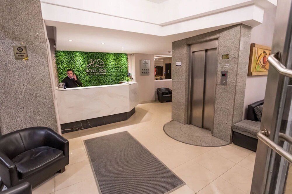 Recepción del hotel con pared verde, mostrador y sillón de cuero
