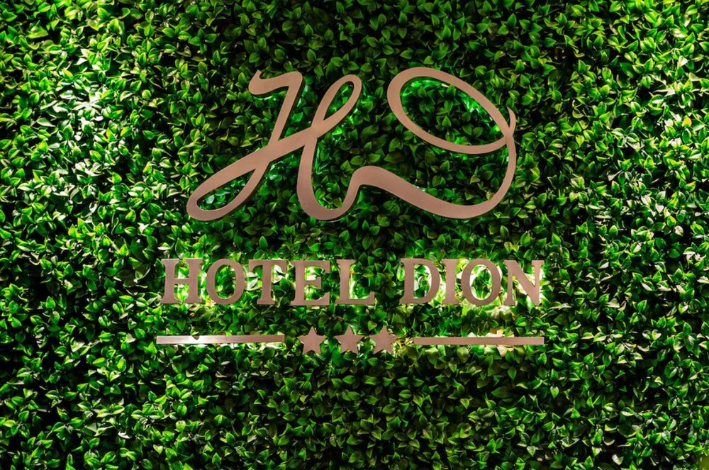 Logo del Hotel Dion sobre un fondo de follaje verde