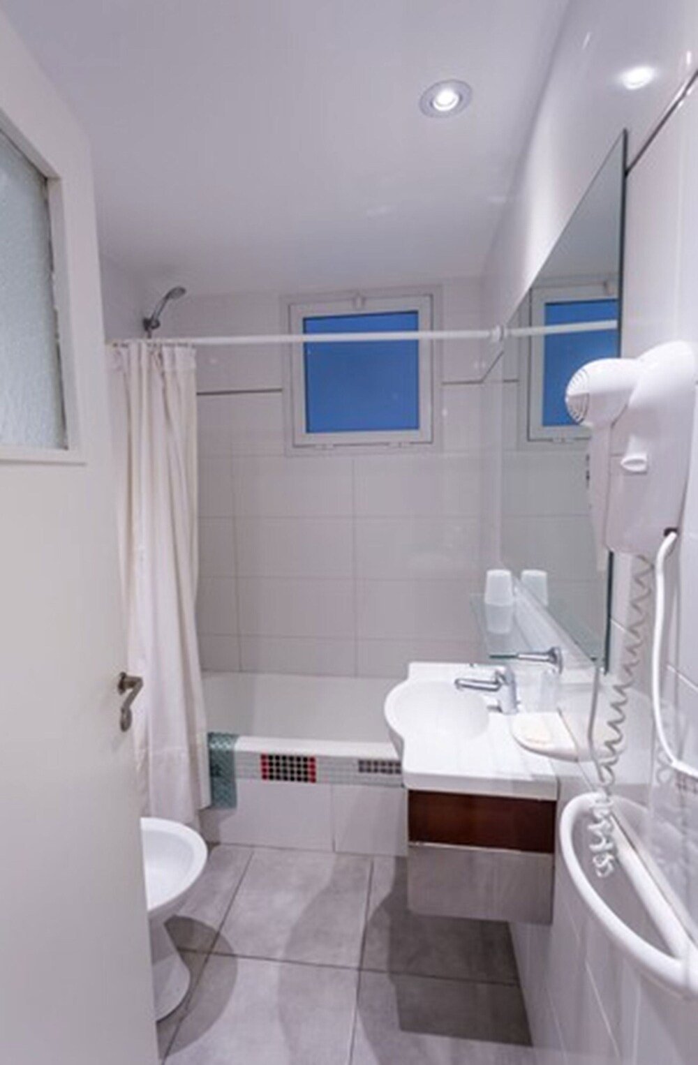 Baño moderno con ducha, lavatorio y espejo del hotel