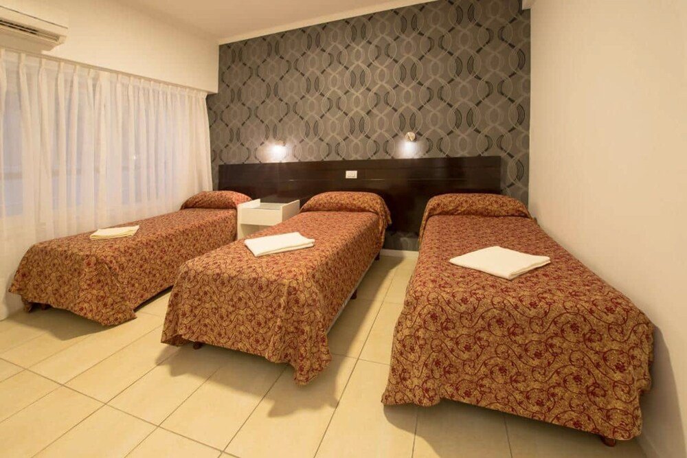 Habitación con tres camas individuales, ventanal y cortinas