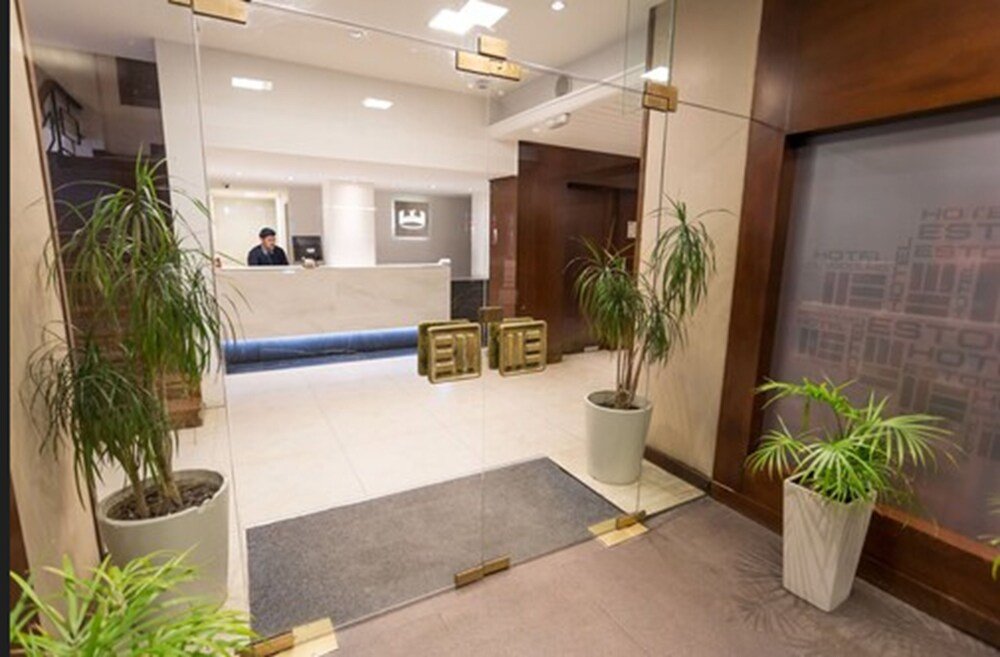 Recepción con mostrador, plantas y espejo grande del hotel