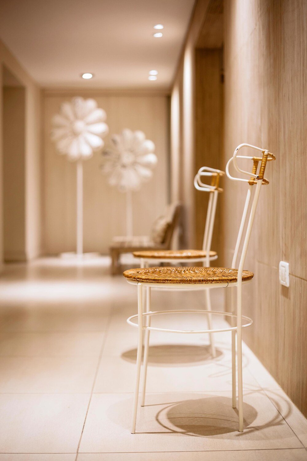 Pasillo con dos sillones de mimbre y una silla blanca