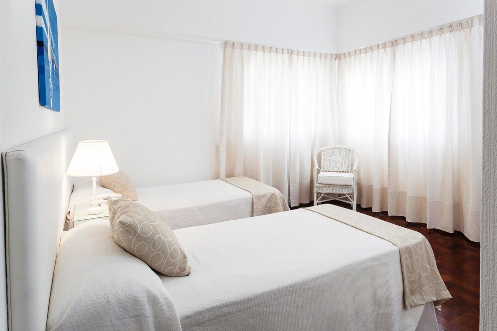 Habitación con dos camas individuales, silla y ventanal