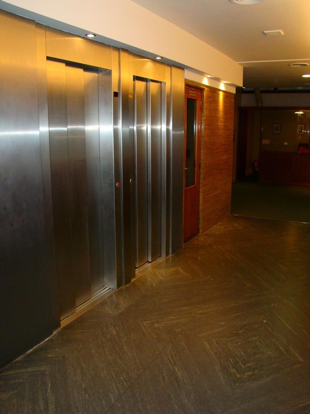 Pasillo con ascensores y puerta de madera del hotel