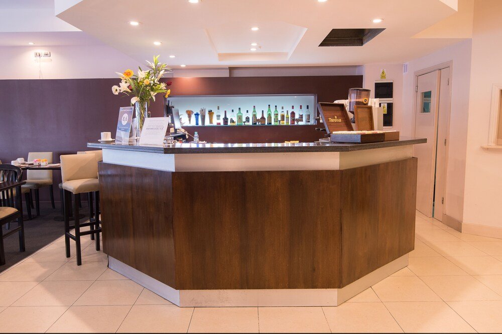 Recepción con mostrador de madera, vitrina con botellas y sector de estar