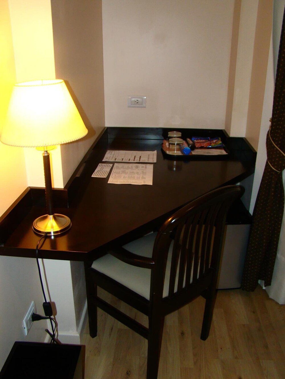 Escritorio de madera oscura con lámpara, silla y algunos snacks