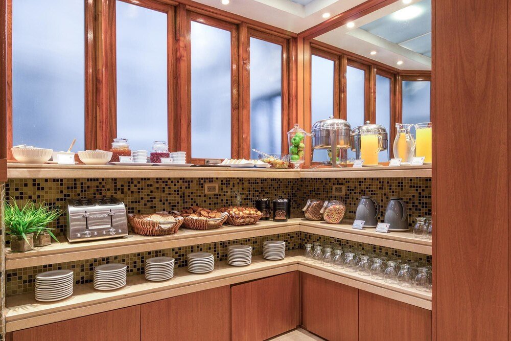 Buffet de desayuno con variedad de alimentos, cafetera y dispenser de jugo