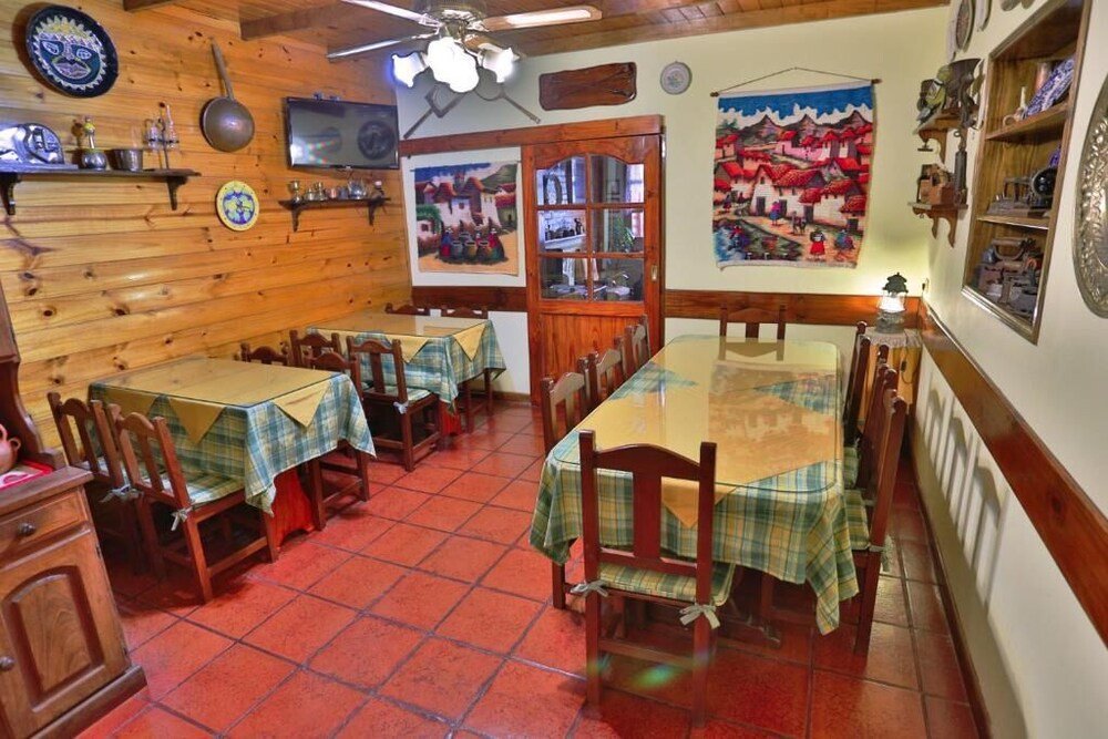 Comedor con paredes de madera, piso de baldosas rojas y mesas con manteles a cuadros
