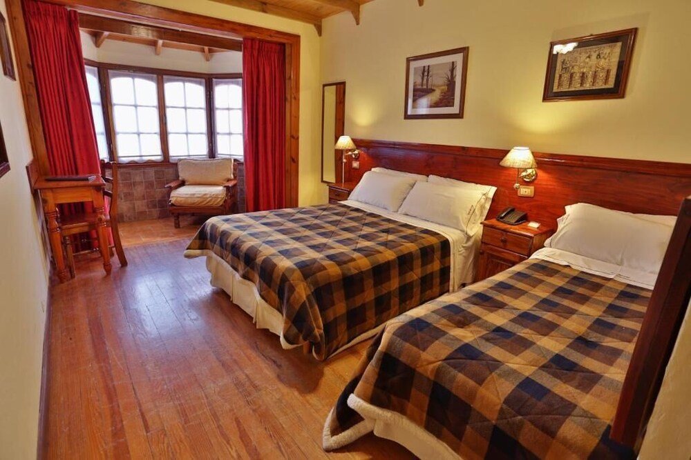 Habitación con dos camas, piso de madera, cabecera de madera y lámparas