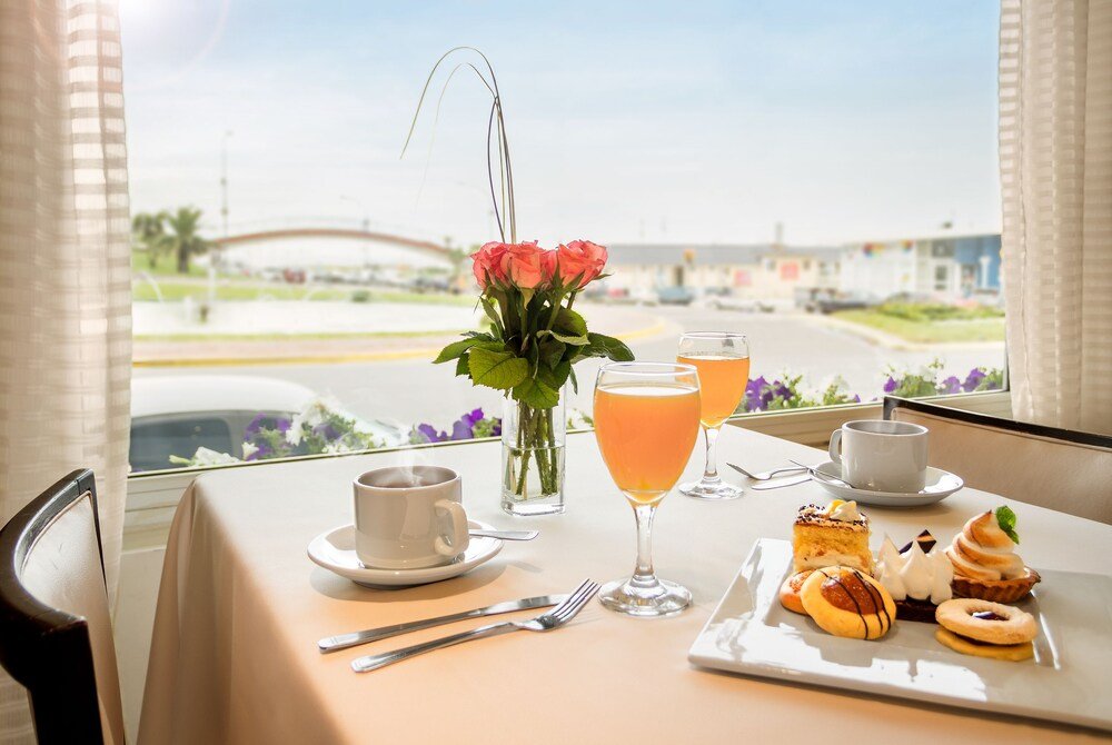 Mesa de desayuno con medialunas, jugo de naranja y copa de vino