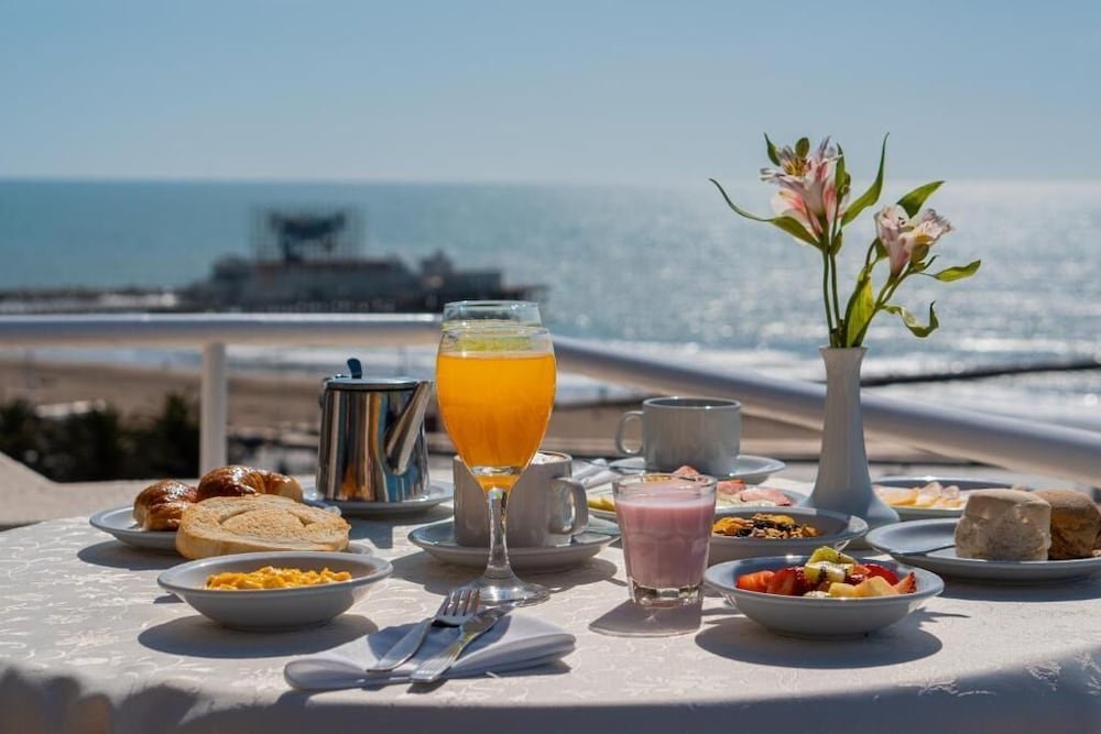 Mesa de desayuno con platos y bebidas frente a una vista al mar