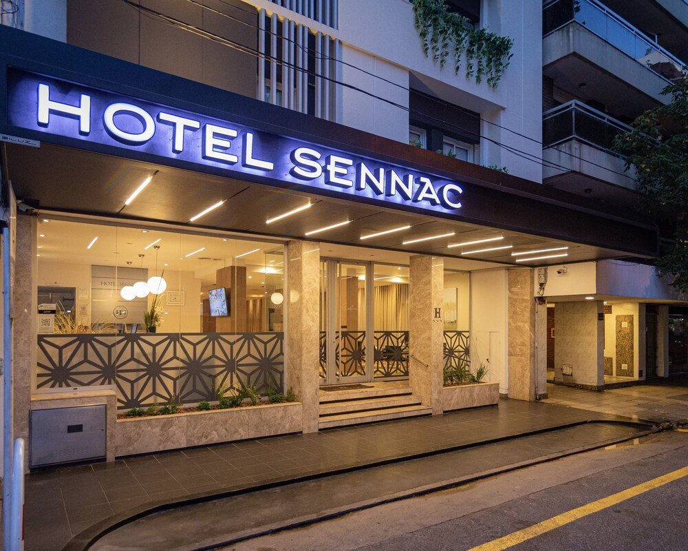 Entrada del hotel con cartel iluminado y fachada de vidrio