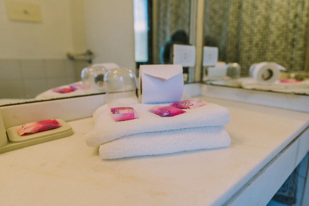 Baño con mesada blanca, espejo y toalla