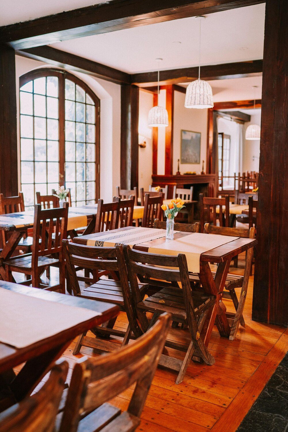 Restaurante con mesas y sillas de madera y ventanales amplios