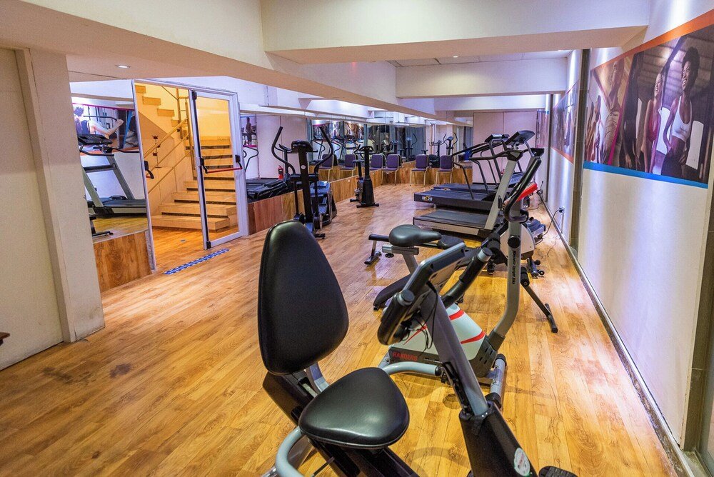 Gimnasio con equipos de cardio, escalera y piso de madera