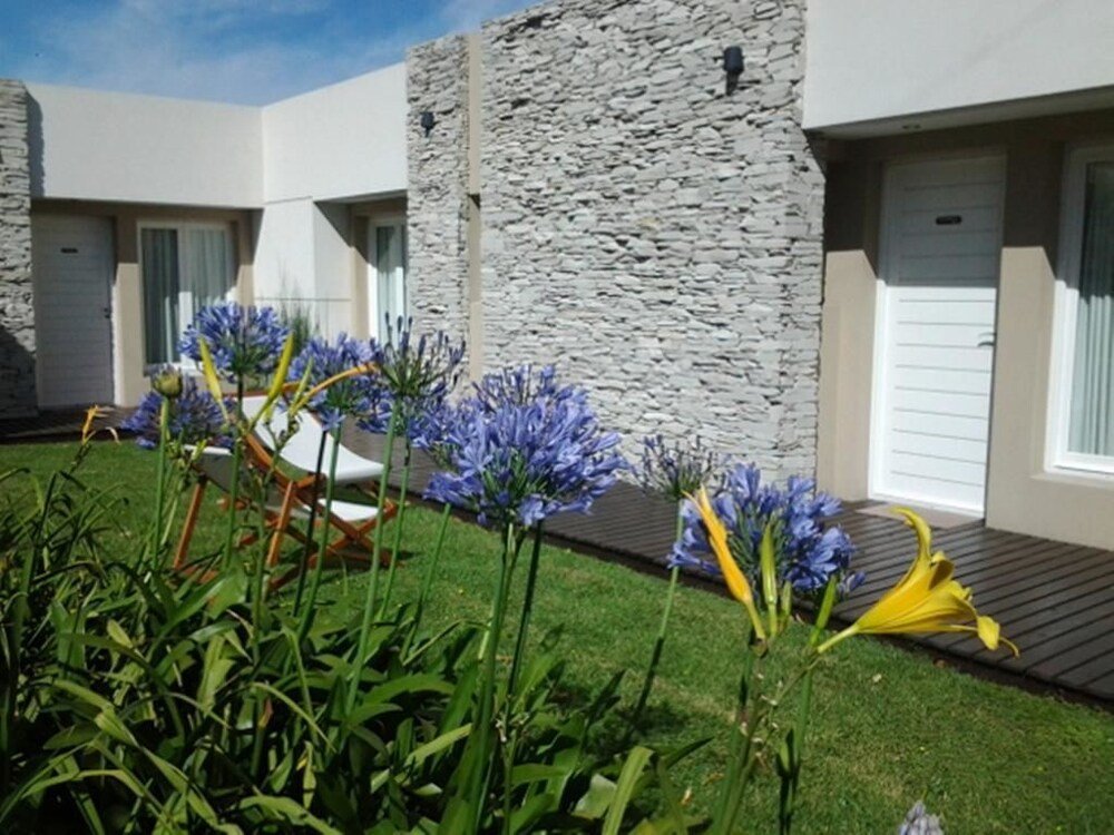 Edificio moderno con paredes de piedra y jardín cuidado con flores