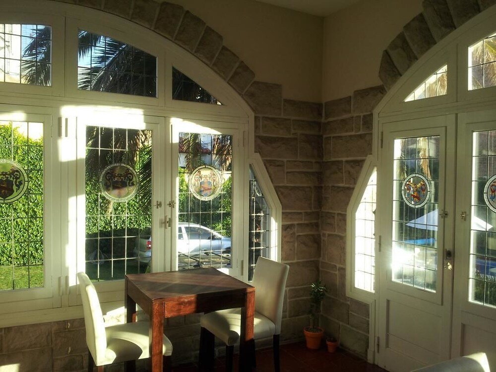 Comedor con mesa y sillas, ventanales con vitrales y pared de piedra